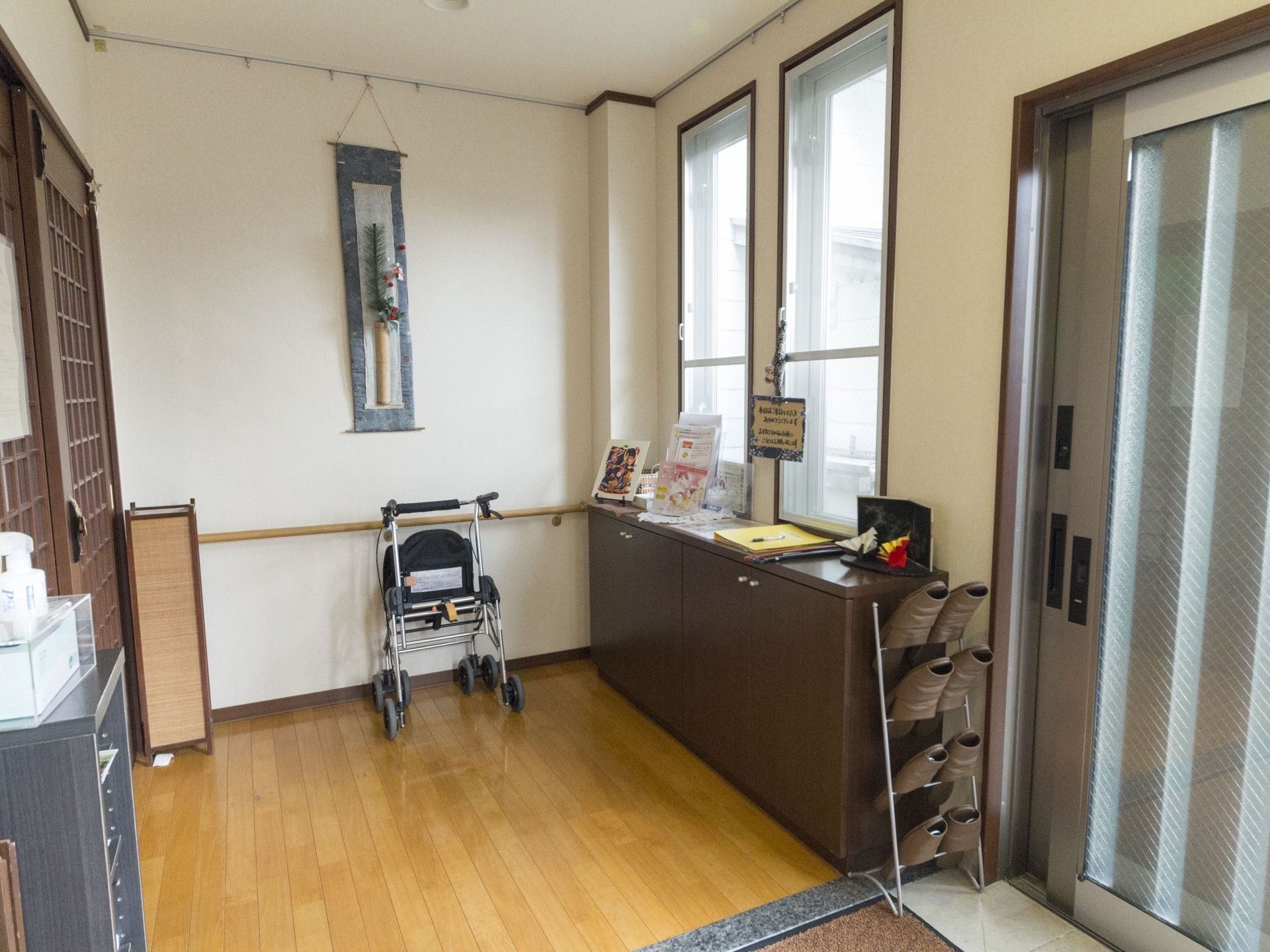 入口の扉は引き戸になっており開いている。フラットで段差のない上り口となっておりスリッパ立てや奥に歩行機が置かれている。