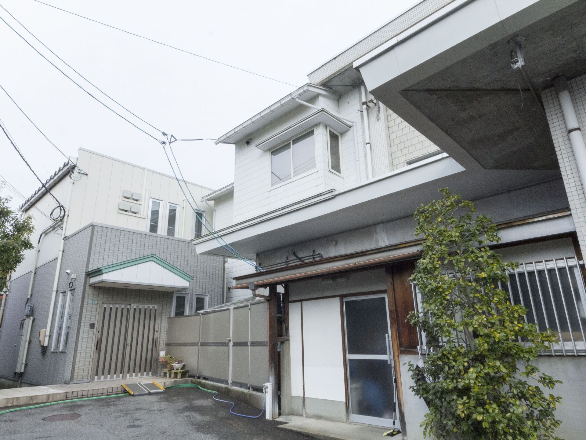 1階がグレー2階が白に切り替えられた外壁、左奥に切妻屋根のひさしの付いた玄関のある建物