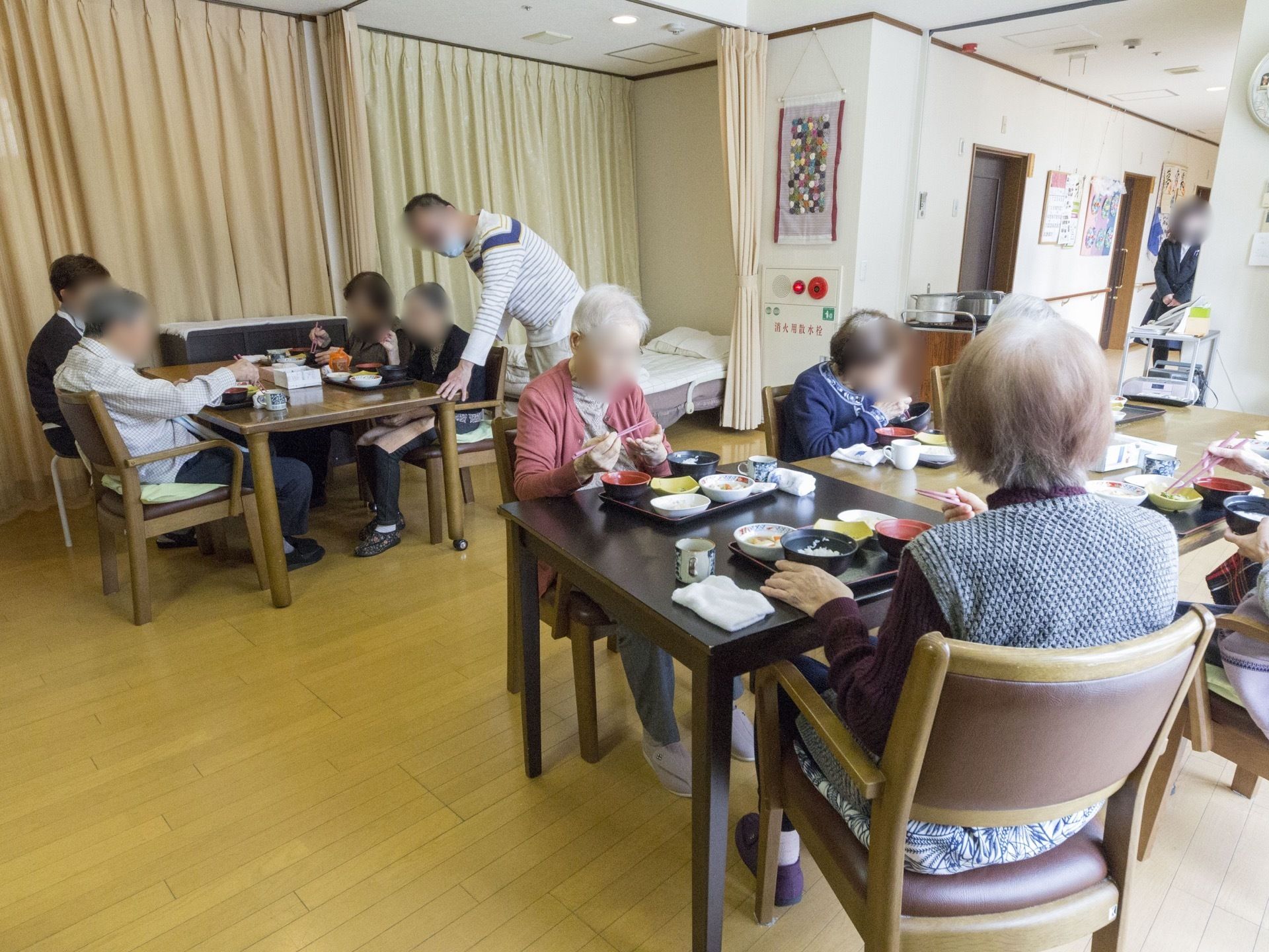 共有スペースの壁には手作りのパッチワーク作品を飾っている。その下には非常用の押しボタンとランプを設置している。