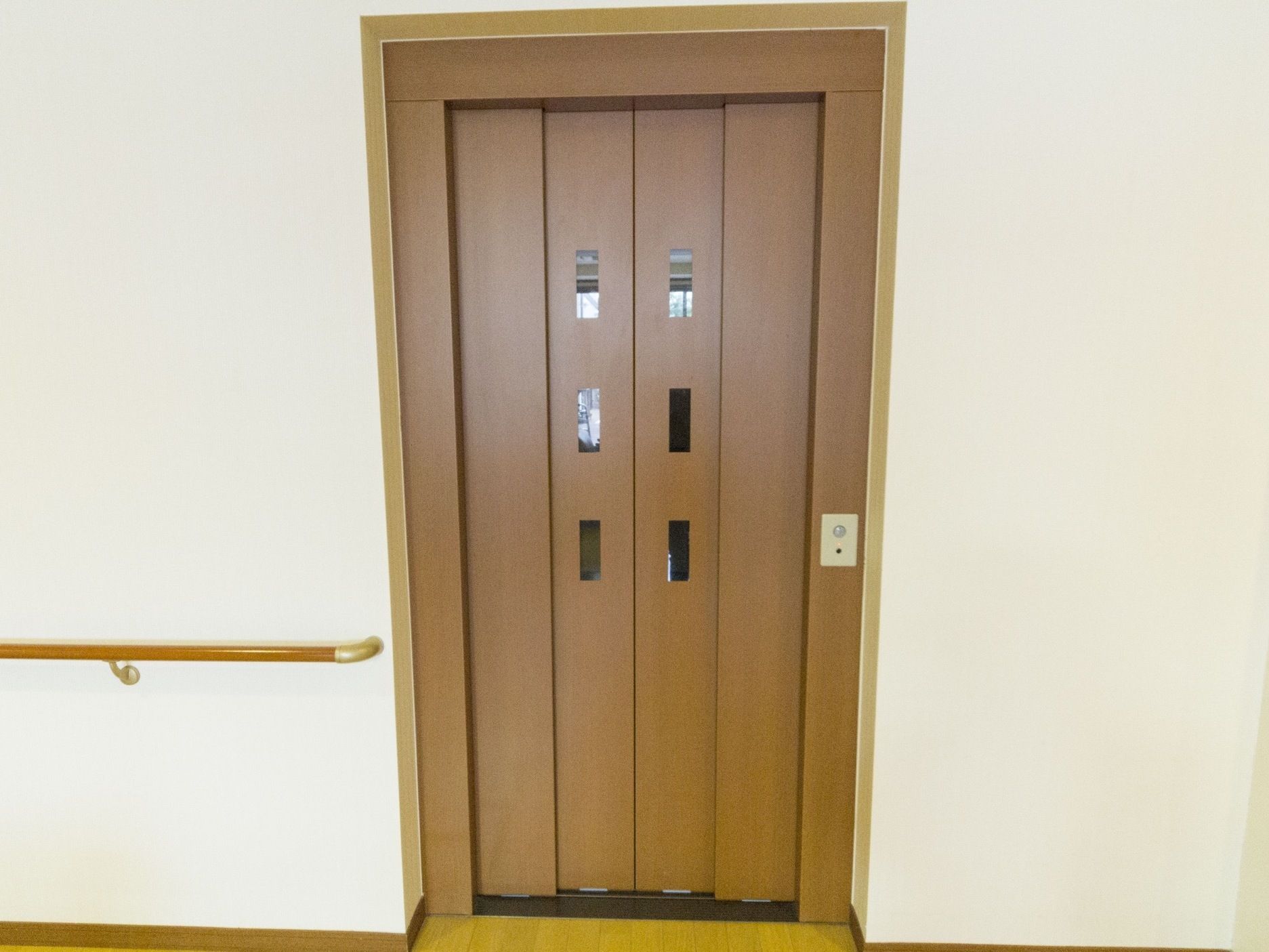 エレベーターの入り口ドアには明るい色調の木材を使っている。小窓を複数設置し、内外の見通しを良くしている。