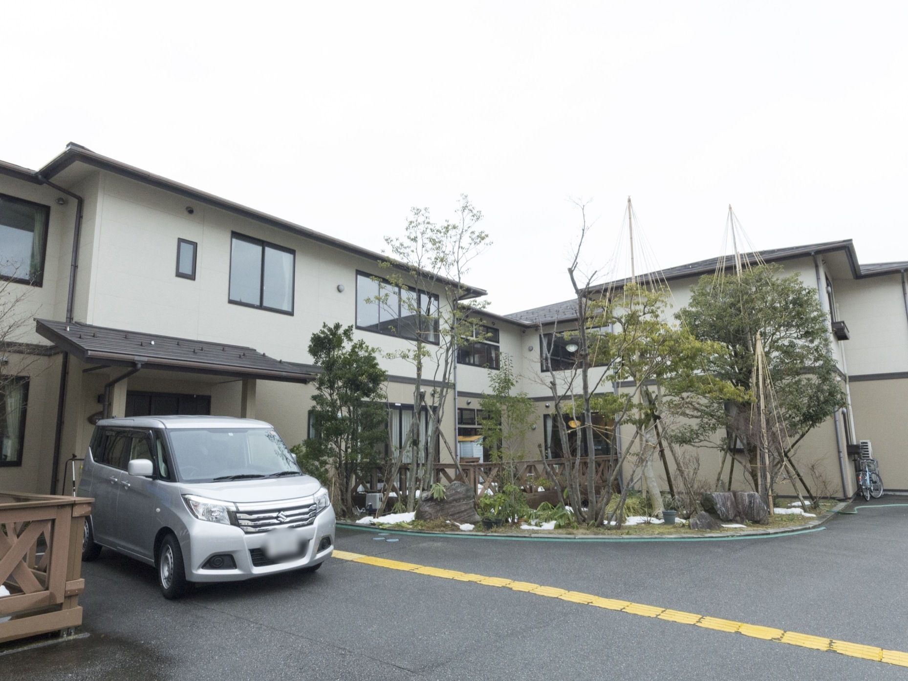 施設の建物は二階建てで、壁の色は落ち着いたベージュ系である。前面には広い空間があり、庭園風に木や石などを配置している。