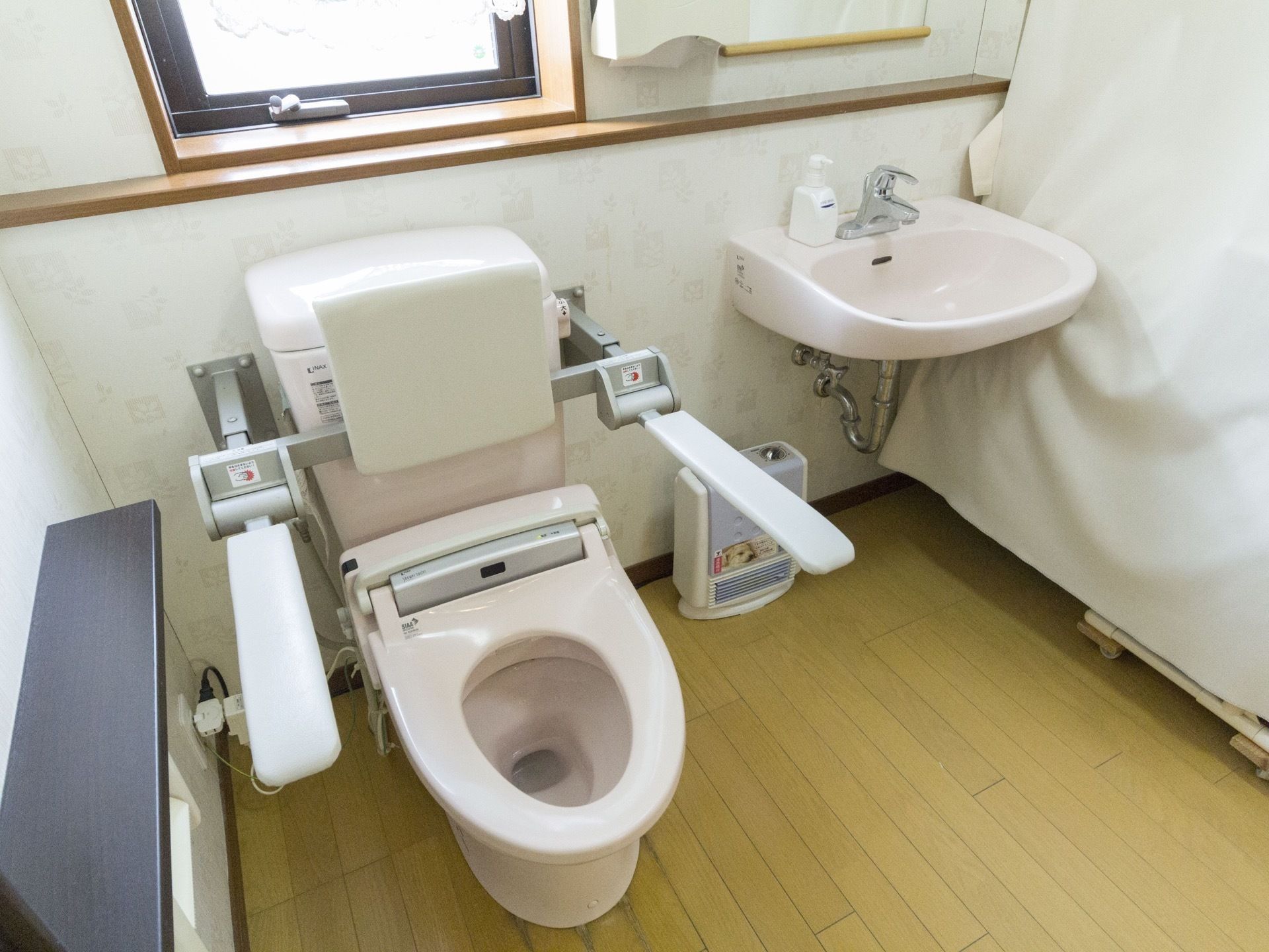 ゆったりと広いトイレスペースに洋式便器と手洗いを設置している。壁には窓を設け、前面に小物を置けるようにしている。