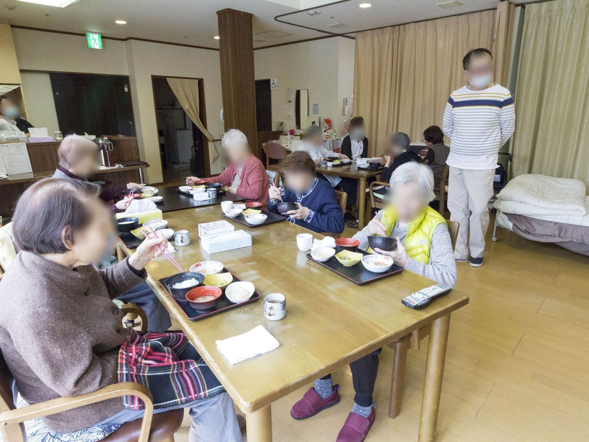 フローリングに置かれたテーブルを囲んで食事をしている入居者