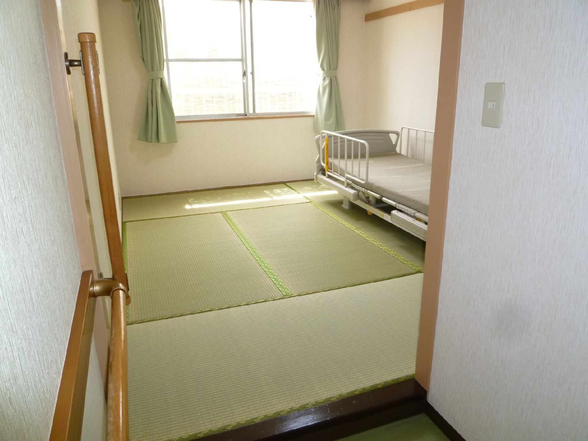 明るい色合いの畳が敷かれた和風の居室である。室内には身体の傾きを調節できるベッドが備え付けられており、転落防止用の柵が取り付けられている。