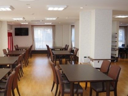 明るい室内に並べられたダークブラウンの４人掛けテーブルと椅子が、部屋全体に落ち着いた印象を与えている。