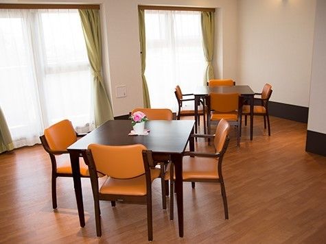 左正面に2つの窓があり、フローリングに4つ椅子がセットされたテーブルが2組置かれた食堂