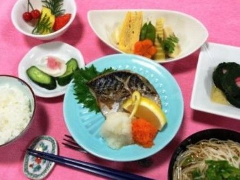 大根と人参のすりおろし、レモン、大葉が添えられた彩りのいい焼サバをメインに、ご飯、麺の入った汁物、炊き合わせ、フルーツなどが並ぶ。