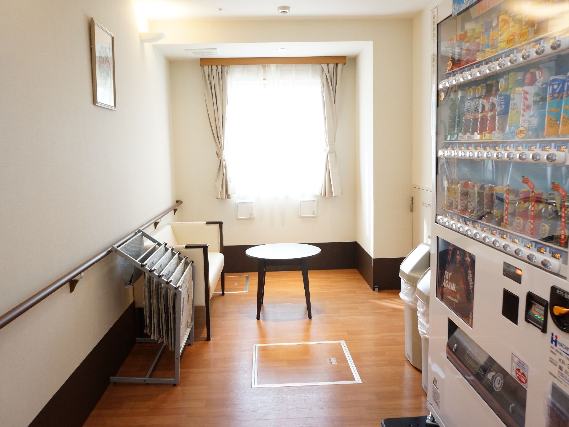 自動販売機があり、奥にはソファに座って休むことができるスペースになっている。窓がある明るい空間である。