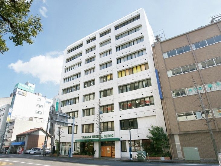 1階に施設名を掲げたひさしの付いた玄関のある9階建ての白いビル
