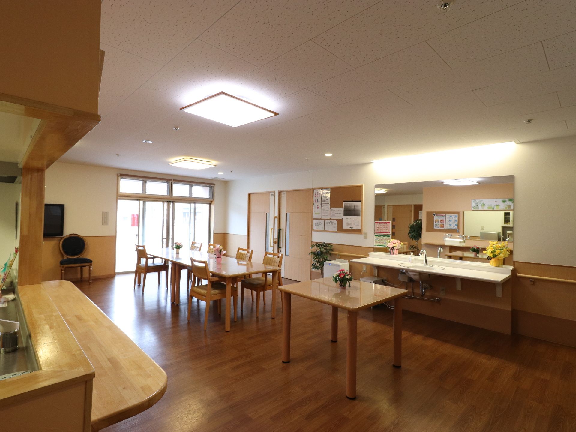 左手前にキッチンのカウンターがあり、部屋の中央にダイニングテーブルが置かれている。カウンターと向かい合った壁側に洗面台が置かれている。