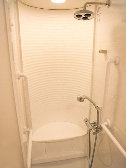 体調の関係で入浴の難しい入居者様向けのシャワーブースである。ピンク色の浴室に合わせた色合いで手すりもついている。