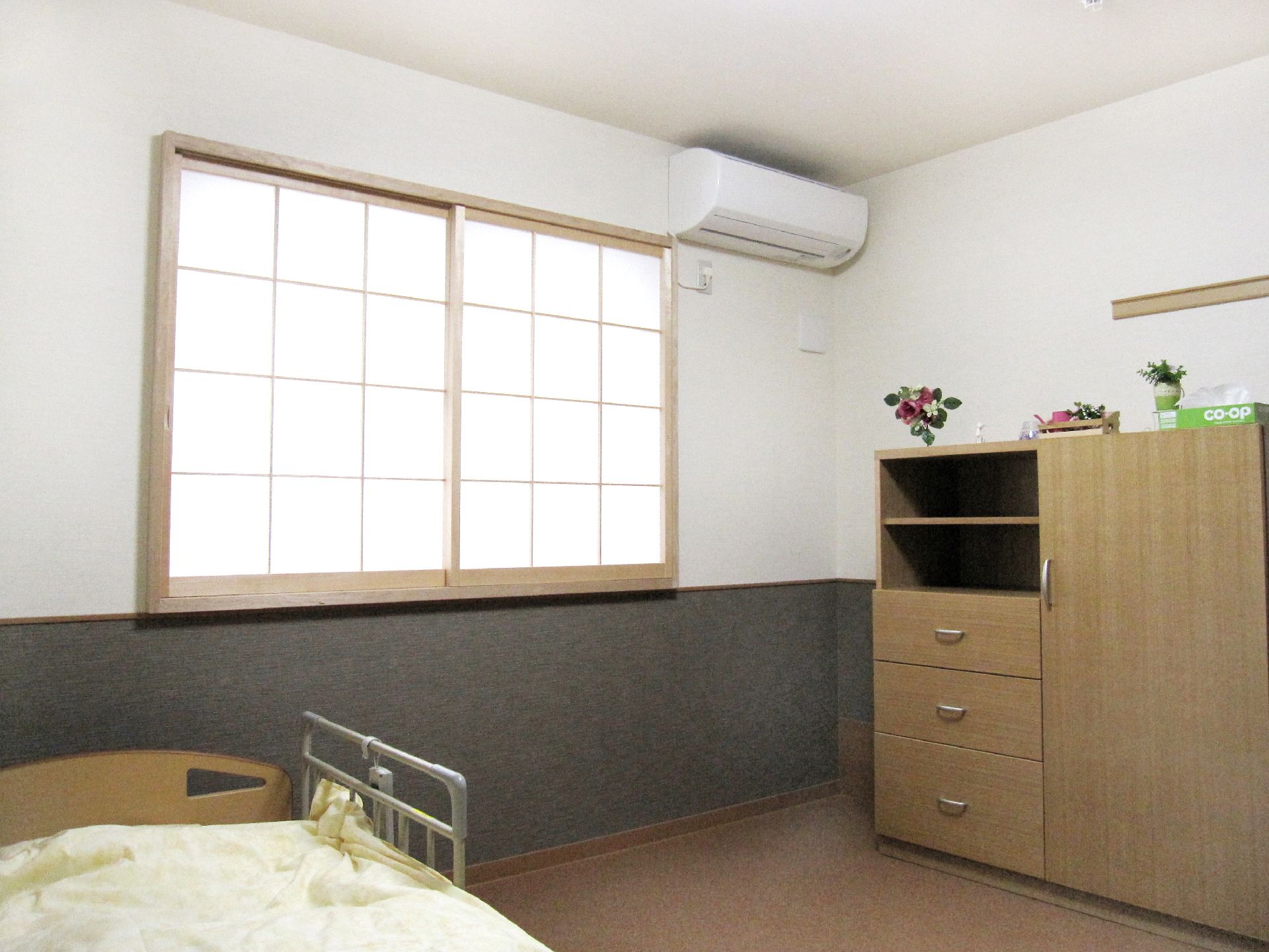室内にはベッドと家具がある。窓は障子風になっており、和室の雰囲気が漂う。エアコンがついているので快適に過ごせる。