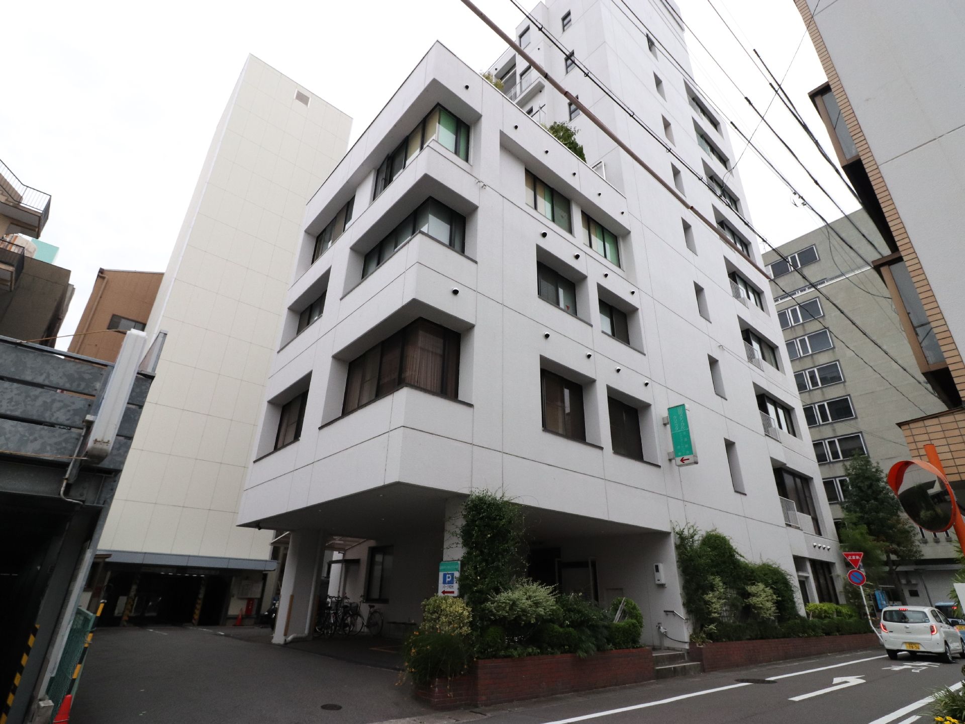 ビルの裏側にまわると、1階部分がピロティになっており、出入口がある。奥に専用の有料駐車場が完備されている。