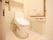 居室のトイレは自動洗浄機能付きの洋式トイレで、壁にはＬ字型の手すりや緊急呼び出しブザーが設置されている。