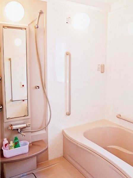個浴型の浴室。手すりが多く取り付けられており、立ち座りを安全に行える。壁には緊急時のための呼び出しボタンがついている。