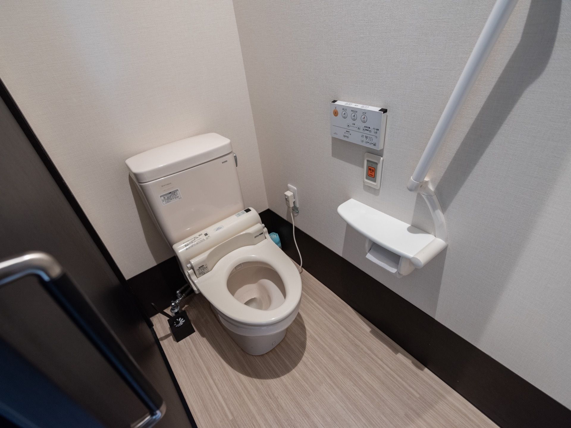 トイレは温水洗浄便座が採用されており、操作ボタンが壁に設置されている。出入り口はダークブラウン色の扉になっている。