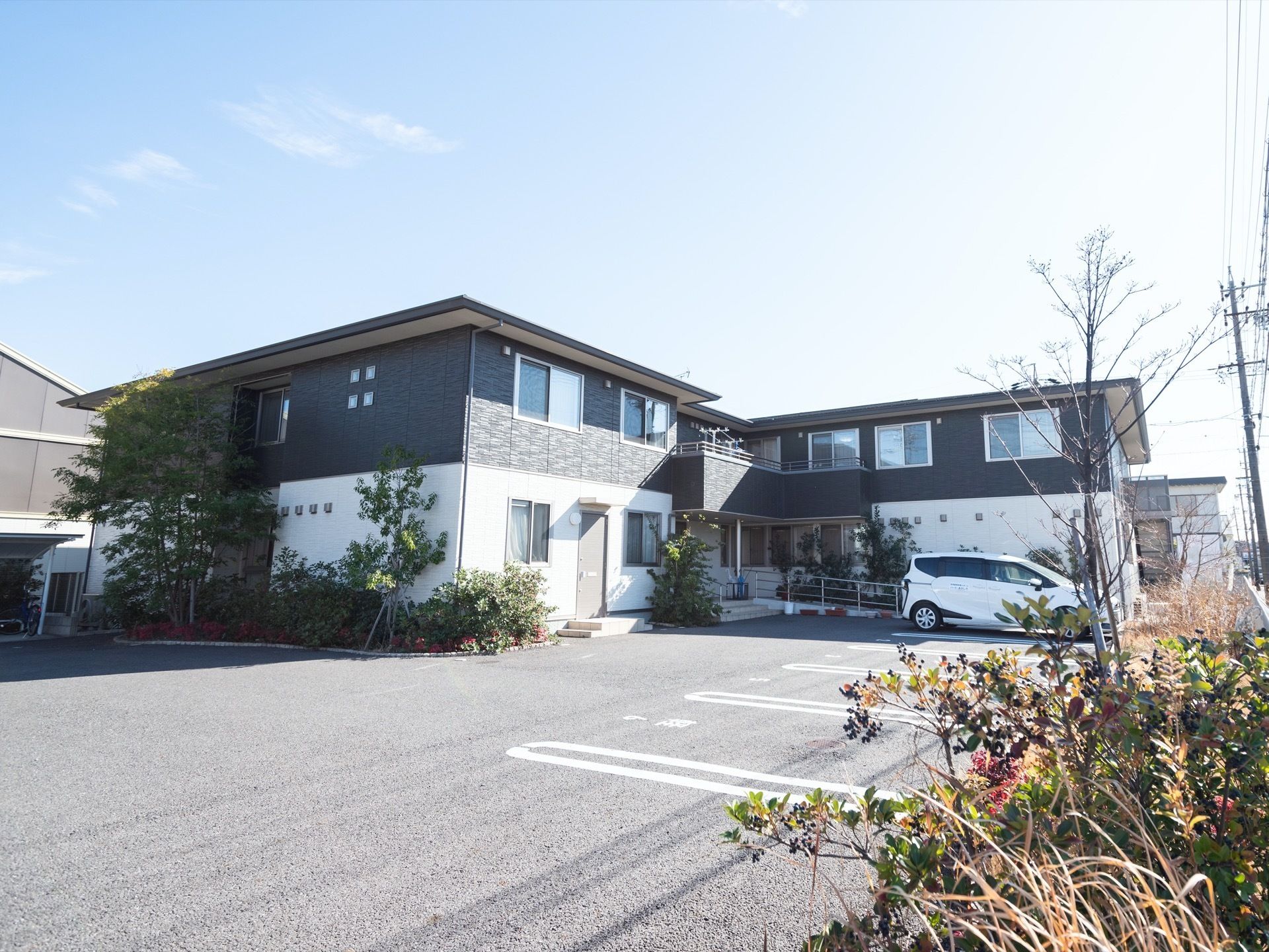 施設はダークグレー色と白色が基調となった２階建ての建物である。２階部分にはベランダが設置されている。