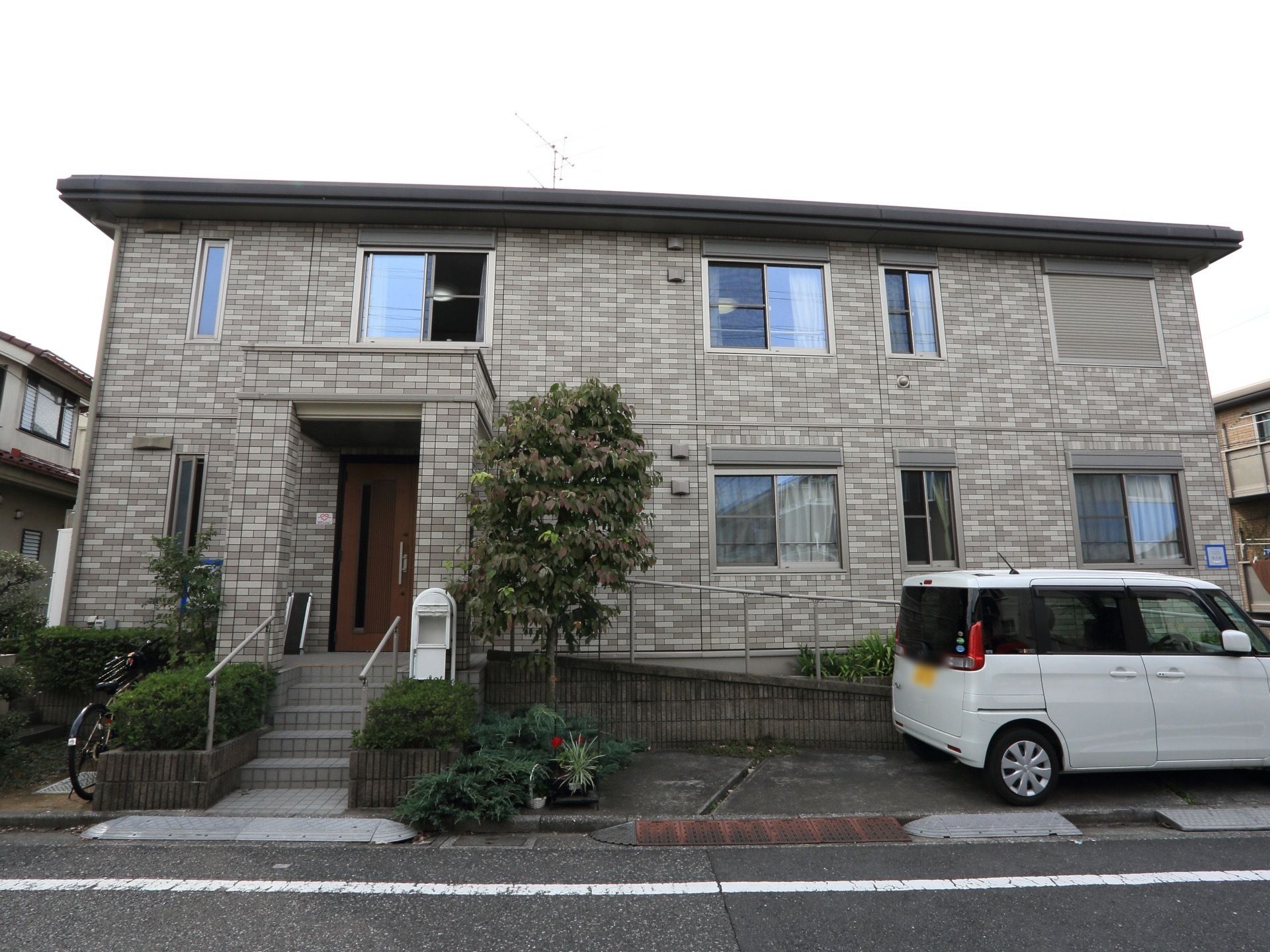 ２階建の二世帯住宅を思わせるような建物である。エントランスの前には植え込みがあり、手すりの付いた階段が設置されている。