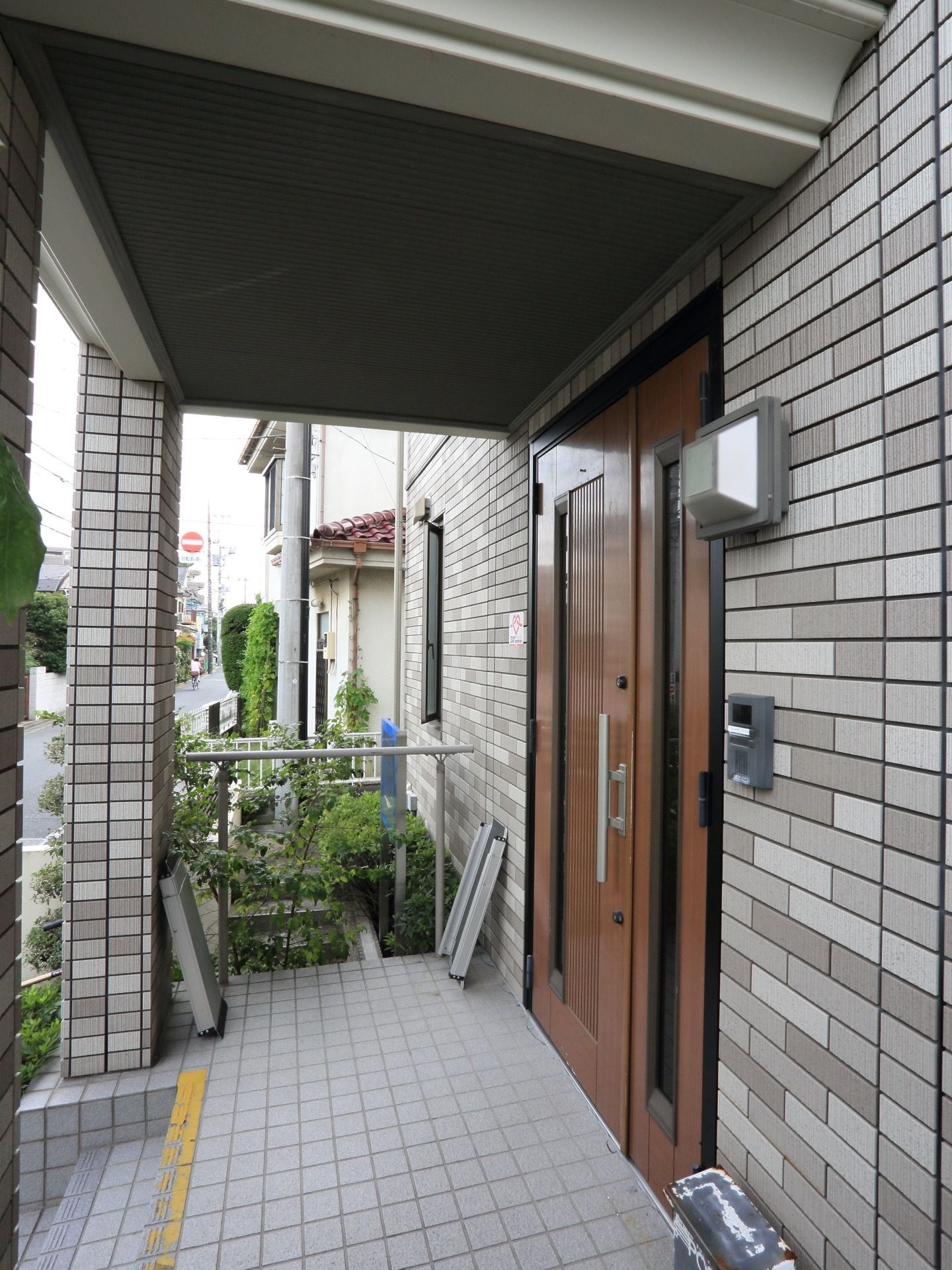 シルバーのタイルの壁がモダンなエントランスである。広い屋根があるので雨の日も濡れる心配がなく便利である。