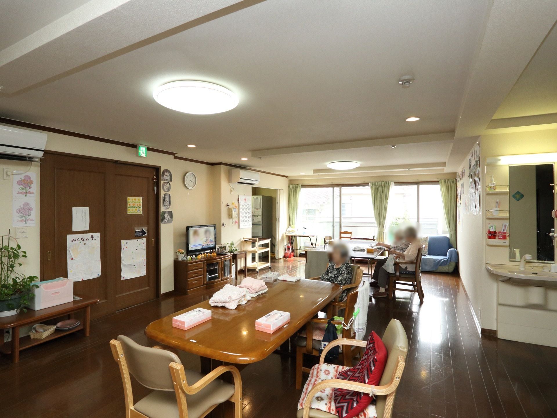 明るく広々とした共有スペースの様子。床はフローリングで、部屋には鏡付きの洗面台が備わっている。エアコンが完備されている。