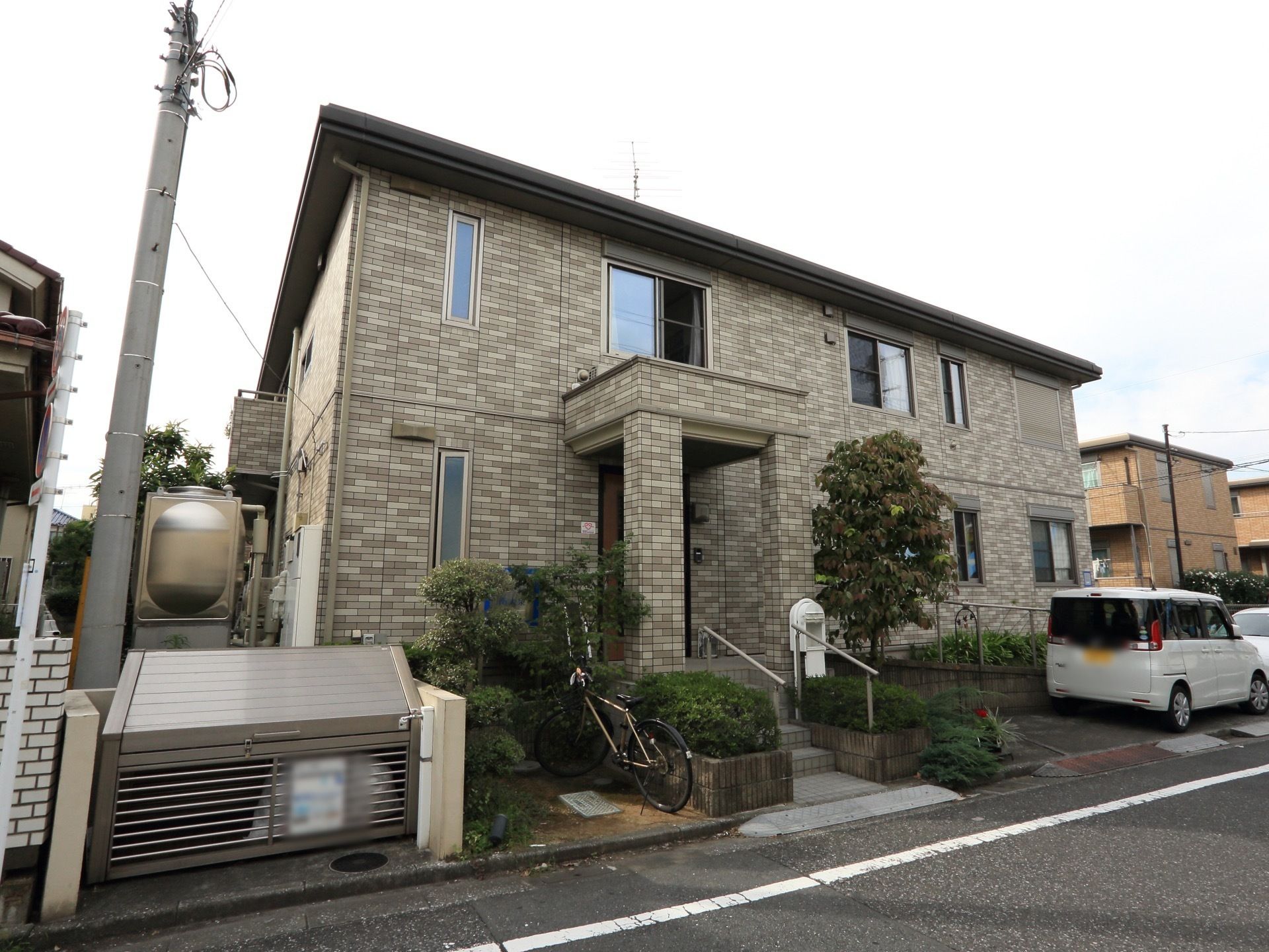 玄関前の階段には手すりが備わっている。居室の窓以外にも、明り取りの窓が設けられている。前に車を数台分停めることができる。