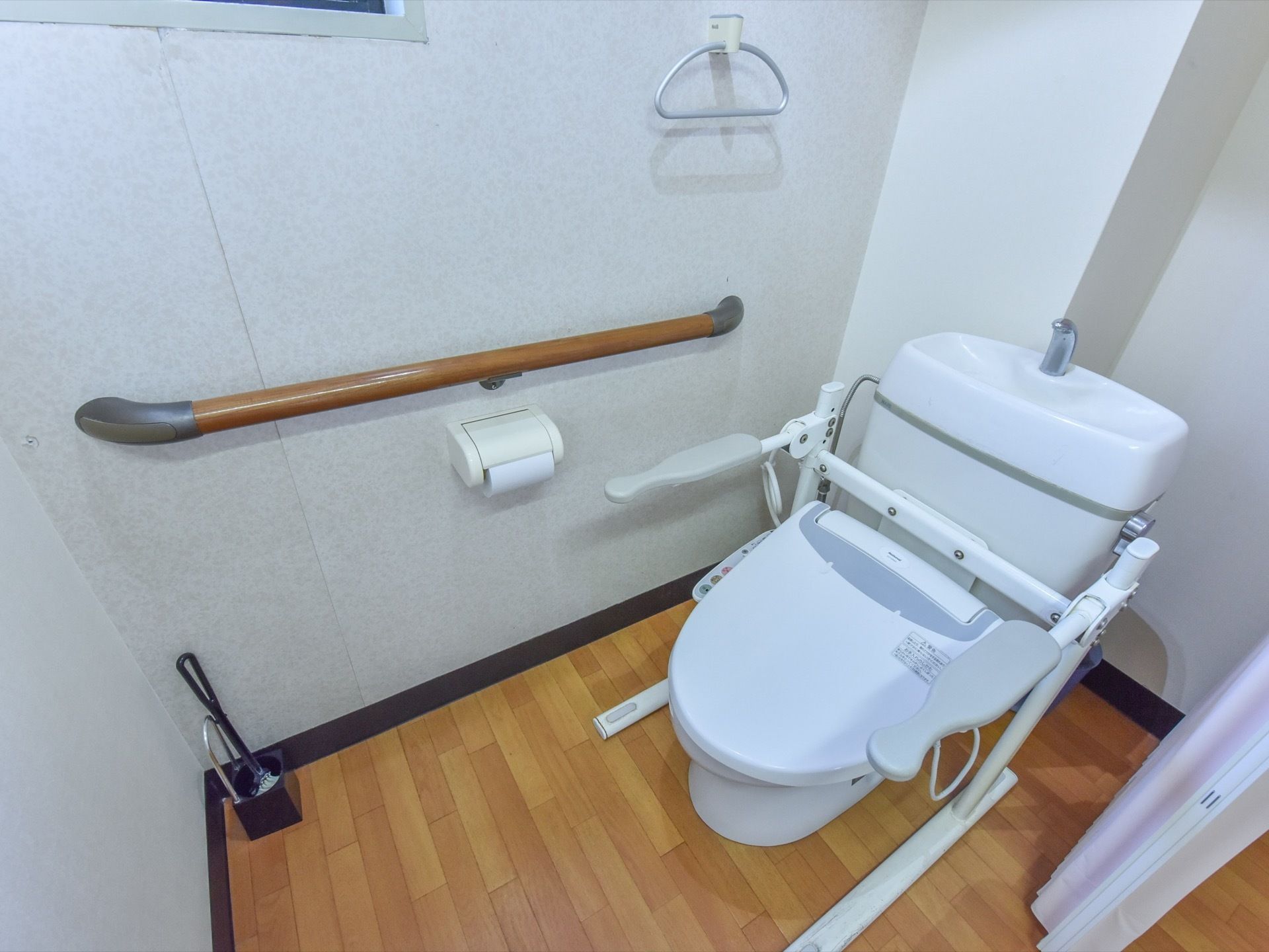 施設のトイレは洗浄機能付を採用。便器には手摺り兼用肘置きがあり、壁にも頑丈な手摺りを設置し安全性に配慮している。