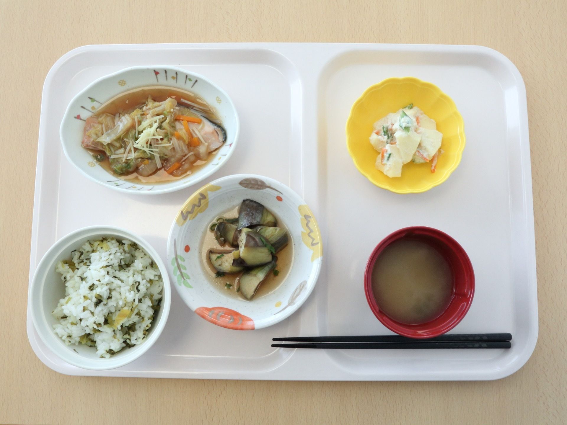ご飯、味噌汁、メインの魚の餡掛け、ナスの煮びたし、サラダがお盆にのっている。可愛い器に盛り付けられている。