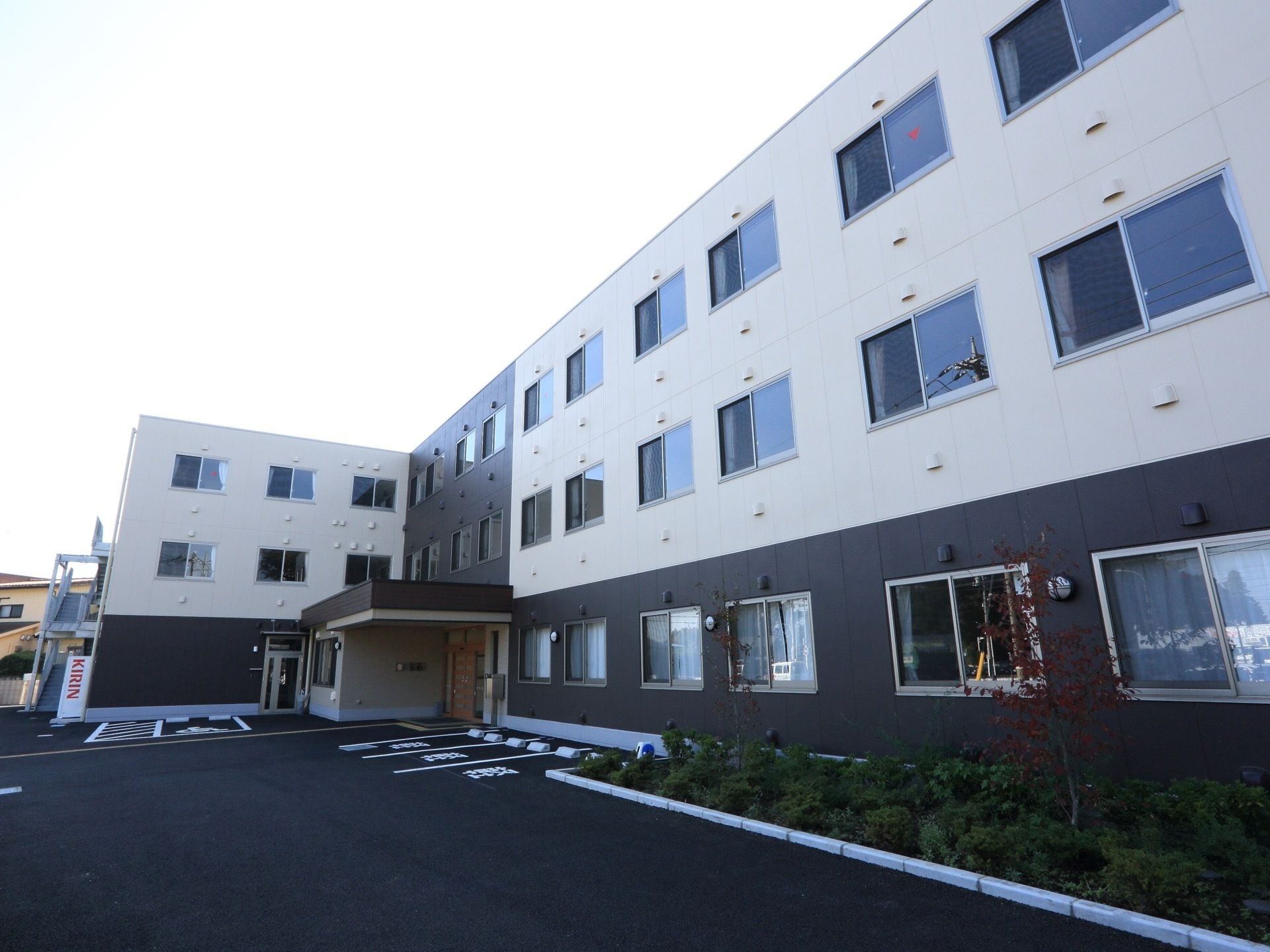 建物の入口付近に駐車場があり、軽自動車専用が３つ、車椅子専用が１つになっている。自動販売機が駐車場の近くにある。