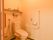 温水洗浄機能付きの便座が採用されているトイレで、上部に手洗い場が設けられている。壁には、L字型の手すりやナースコールが設置されている。