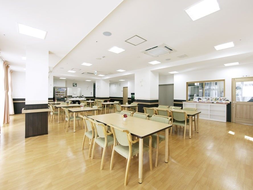一面を大きな窓で囲まれた部屋に、いくつものテーブルと椅子が配置されている。また壁際には手すりが設置してあり安全面にも配慮されている。
