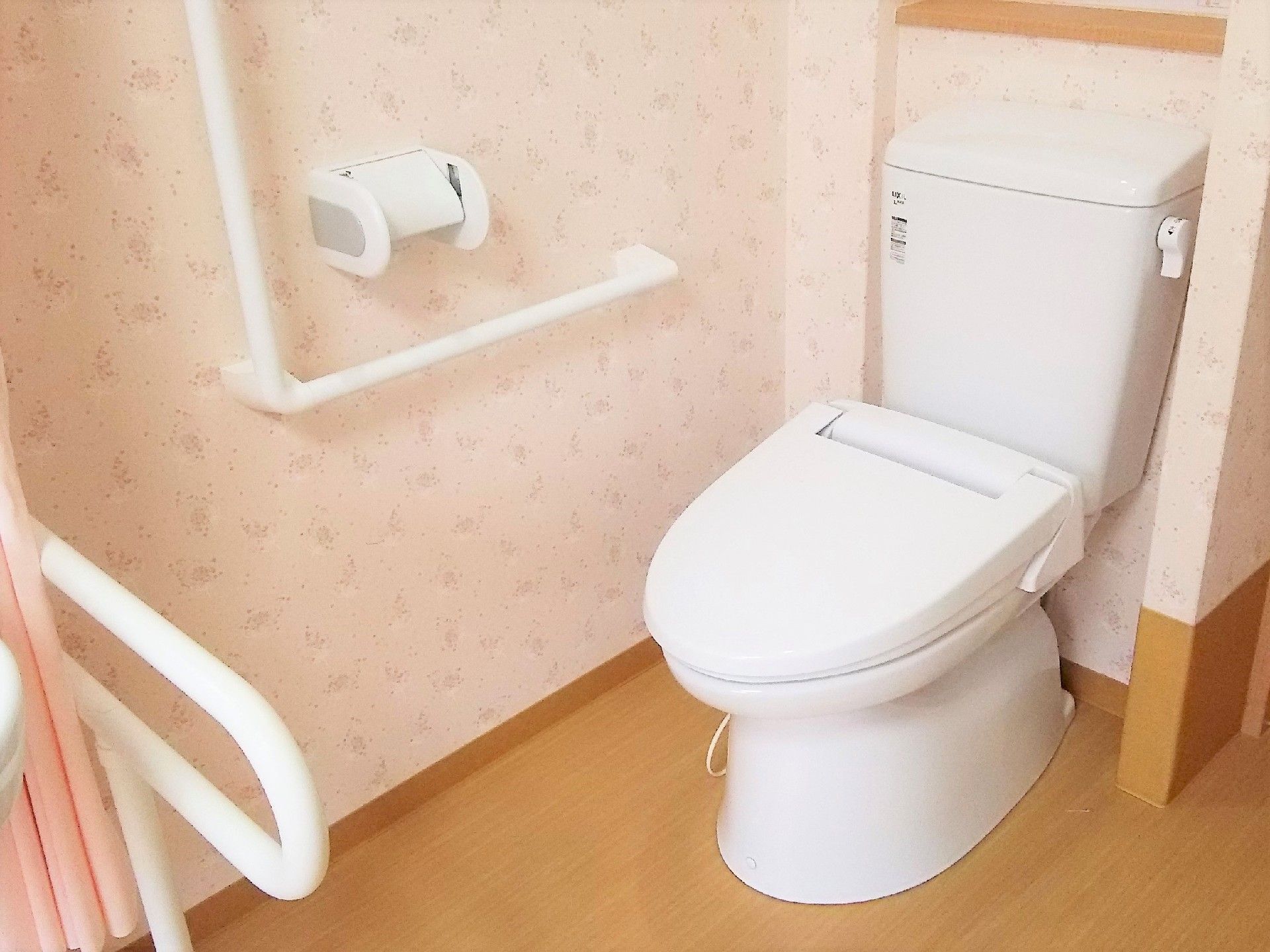フローリングの床はバリアフリー構造となっている。ペーパーホルダーの近くと便器正面には手すりが設置されている。