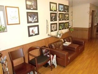 茶色のイスとソファが並び、壁にさまざまな写真が飾ってある廊下スペース