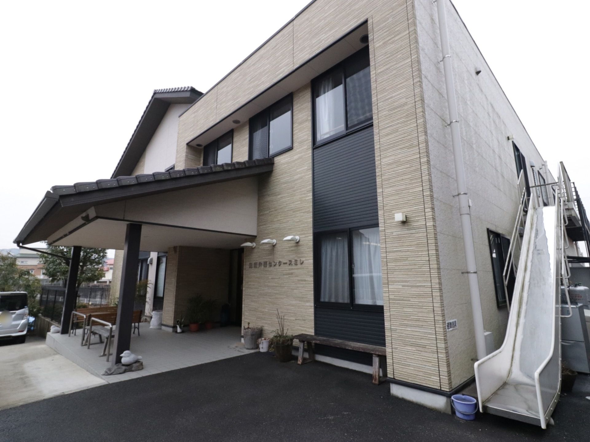 大きなひさしが特徴的な2階建て。段差を無くし、車椅子でも安全に移動することができる。外部には避難用滑り台を設置している。