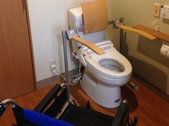 スペースにゆとりのあるトイレには温水洗浄便器が設置されており、背もたれの付いた手すりとナースコールボタンが完備されている。