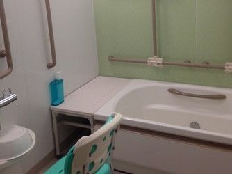 さわやかなミントグリーンがポイントカラーになっている浴室。手すりは壁をはじめ浴槽内にまで完備されシャワーチェアーも用意されている。