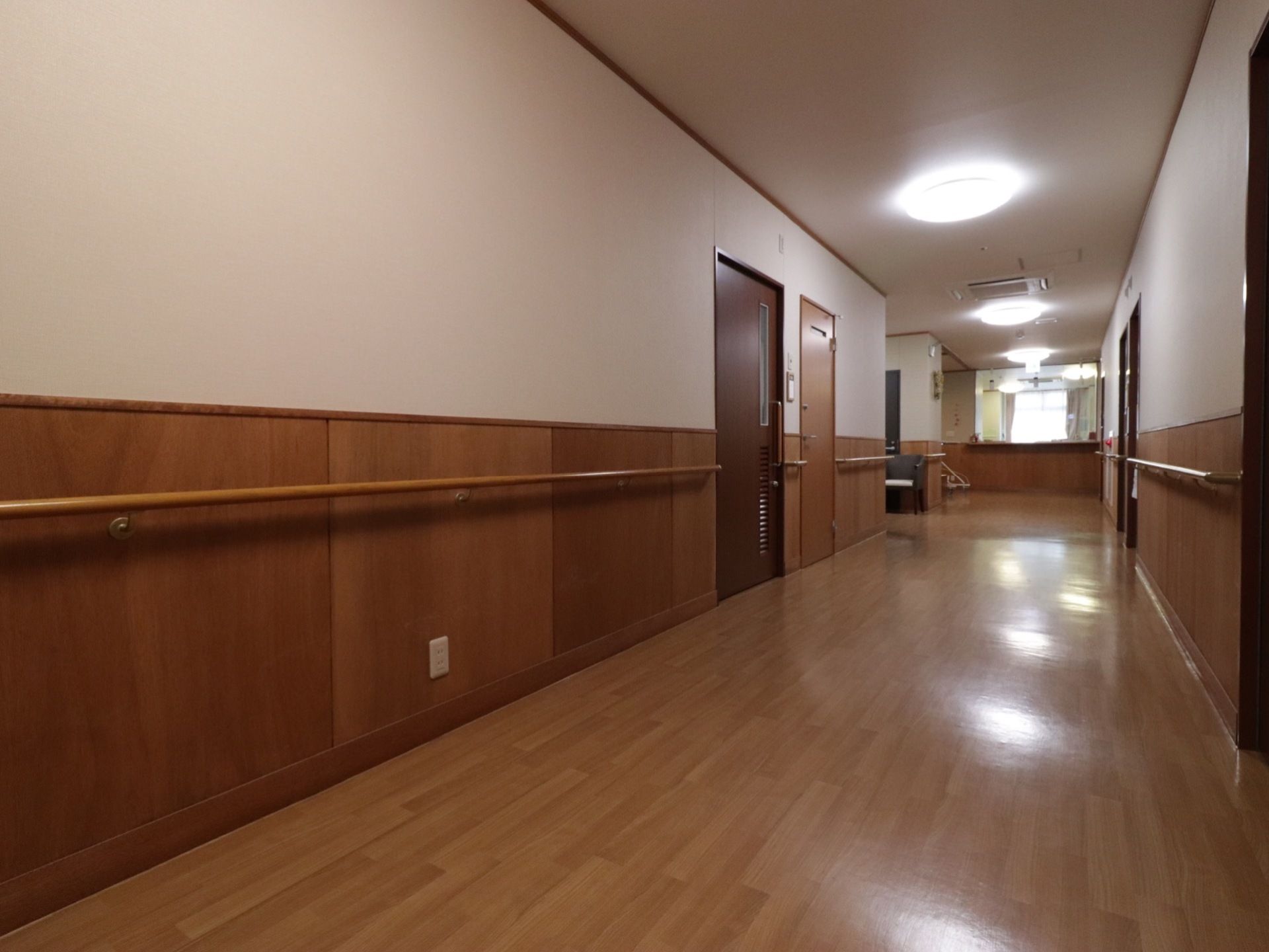 通路は幅が広く、手すりが設置されている。床、壁、手すり、扉は木目調で統一されている。一般的な住宅と変わりのない、温かみが感じられる。