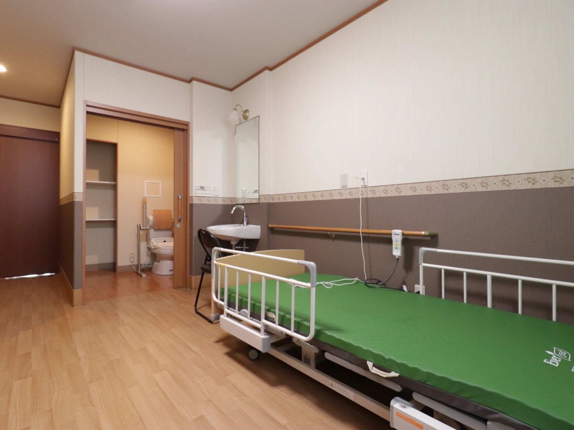 電動ベッドが置かれている。トイレや洗面台が設置されている。床はフローリングで安全に移動しやすい造りとなっている。