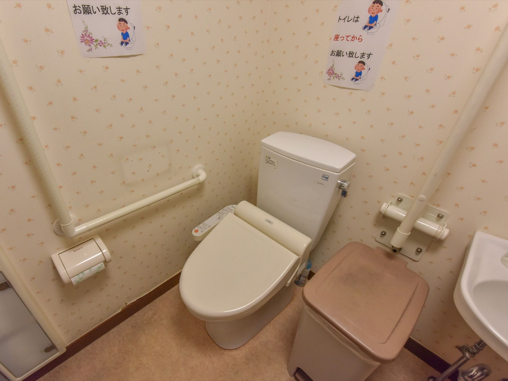 清潔なトイレには、温水洗浄便座の装備されて便器が設置されている。壁には、注意を促すポスターが貼られている。