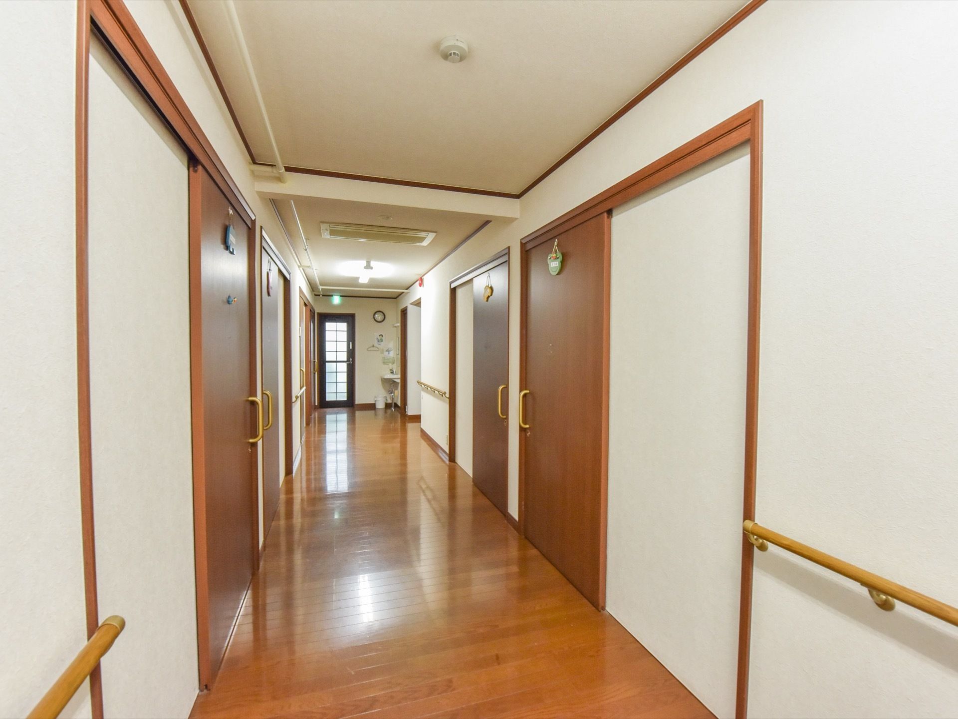 通路の両側には、居室がある。天井にはエアコンがある。奥には洗面台があり、手洗いや手指の消毒が出来る。