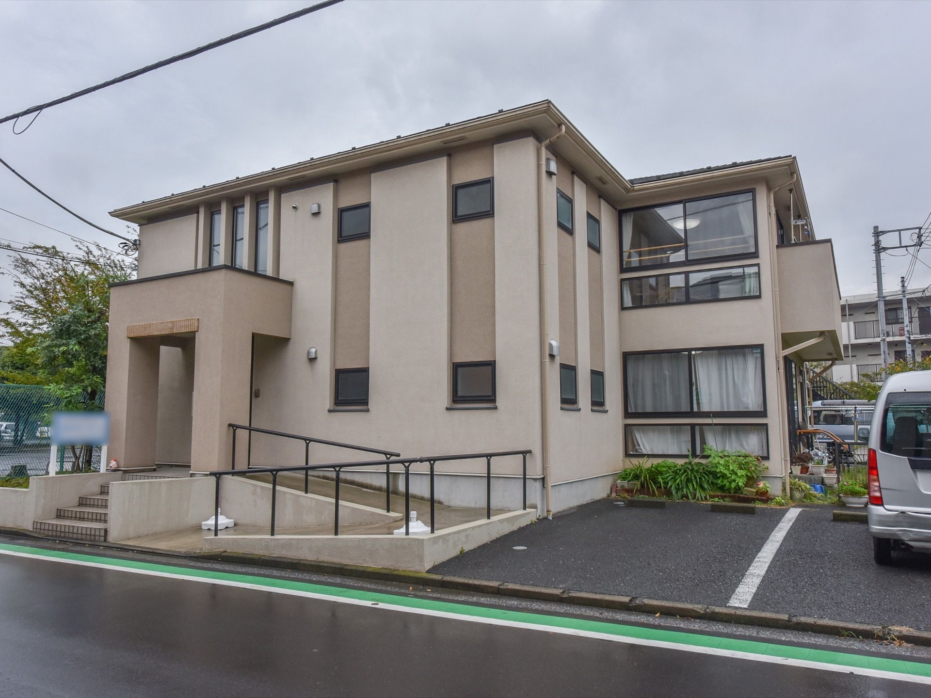 ２階建ての建物で、大きな窓が特徴的である。専用の駐車場がある。玄関前には、手すりの付いたスロープがある。