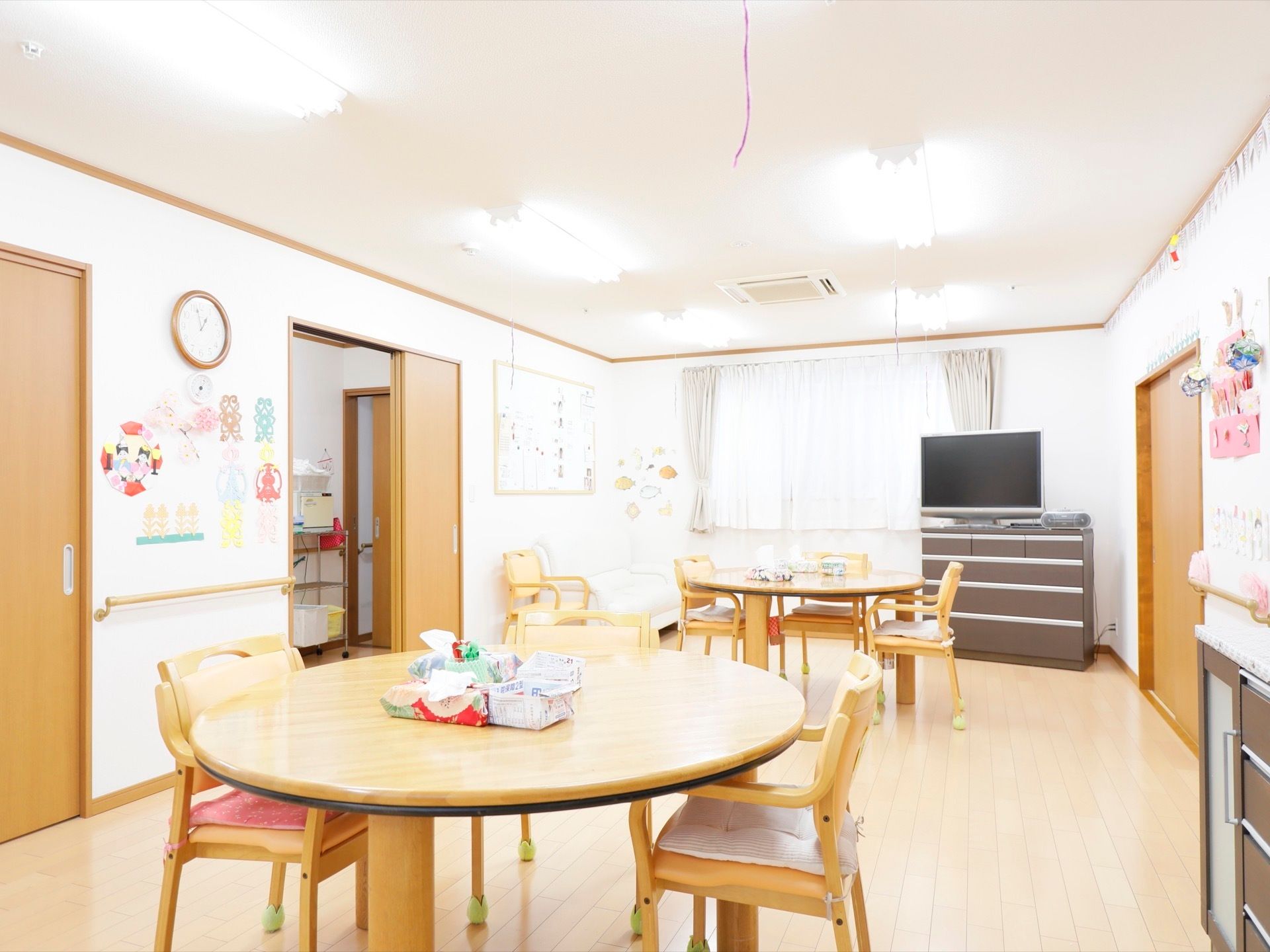 円形のテーブルを囲むように椅子が置かれている。奥には窓があり、隣にテレビ、ラジカセが用意されている。