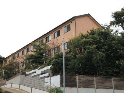 坂の上に位置した周りを木に囲まれたオレンジ色の建物