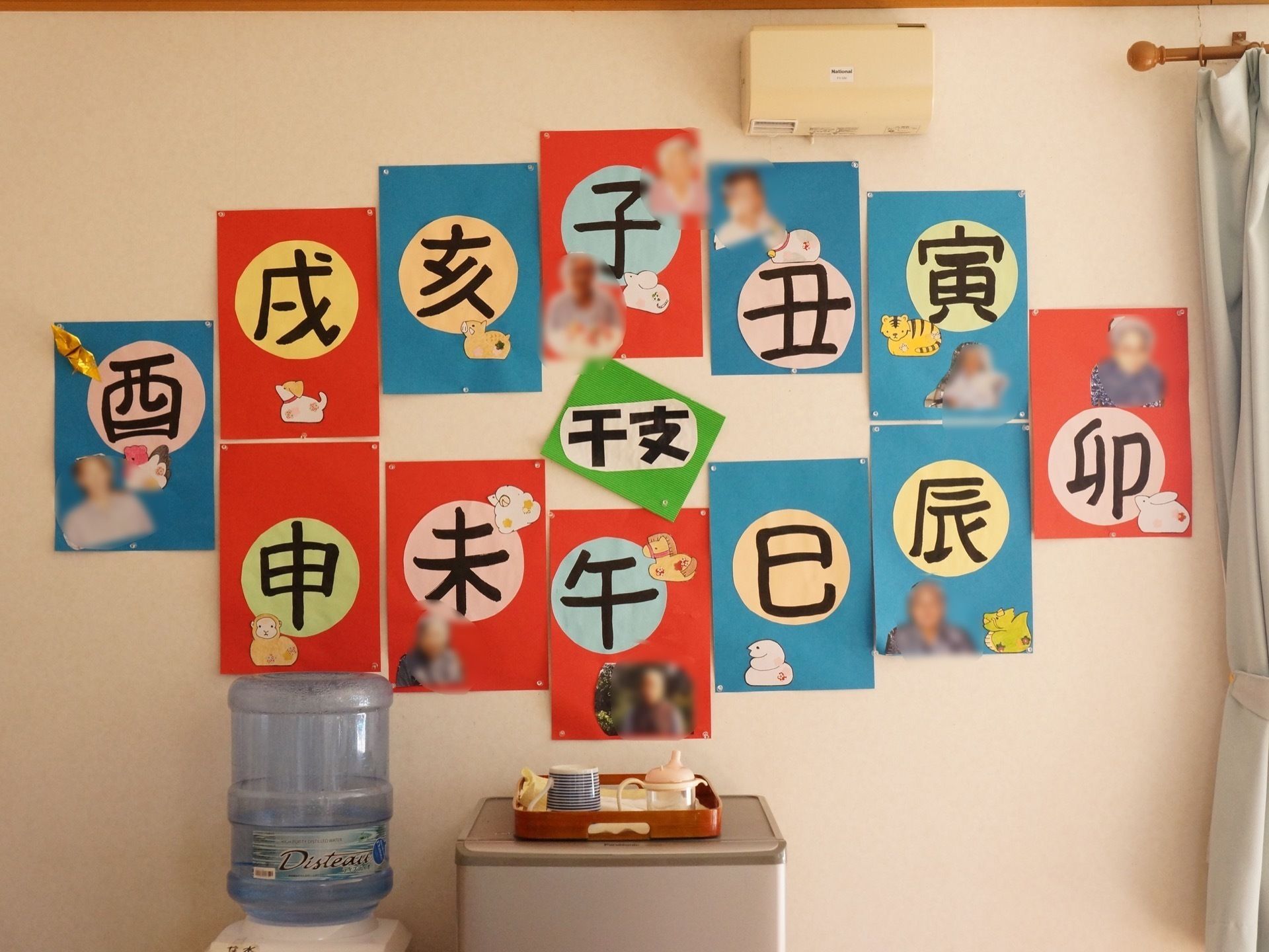 １２支の干支の漢字とイラストが書かれた画用紙に入居者の顔写真が貼られた展示品