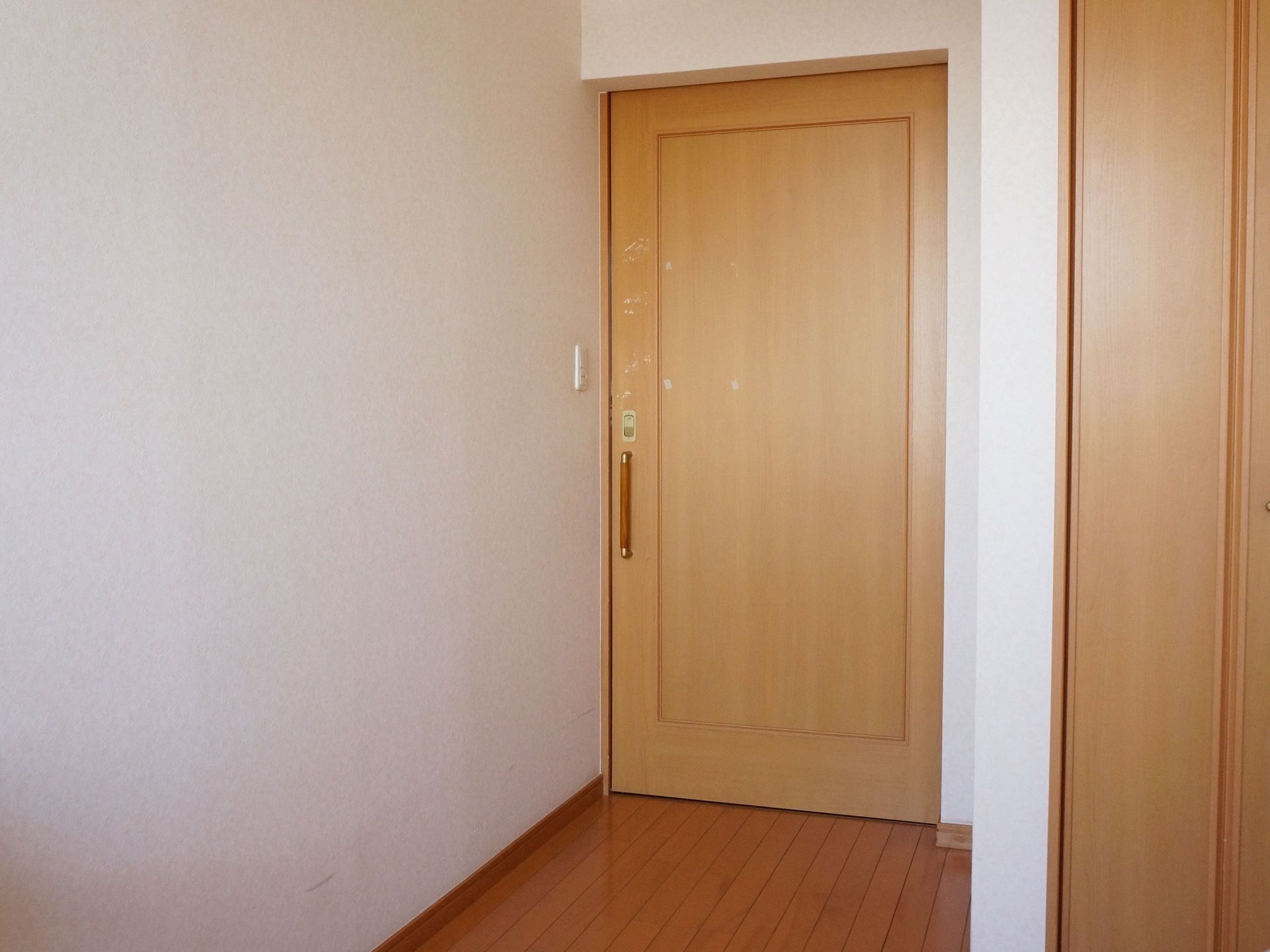 居室のドアには、縦向きに取っ手がついている。取っ手には、メタリックの金のパーツが見えており、手で掴む部分は落ち着いたカラーのブラウンである。
