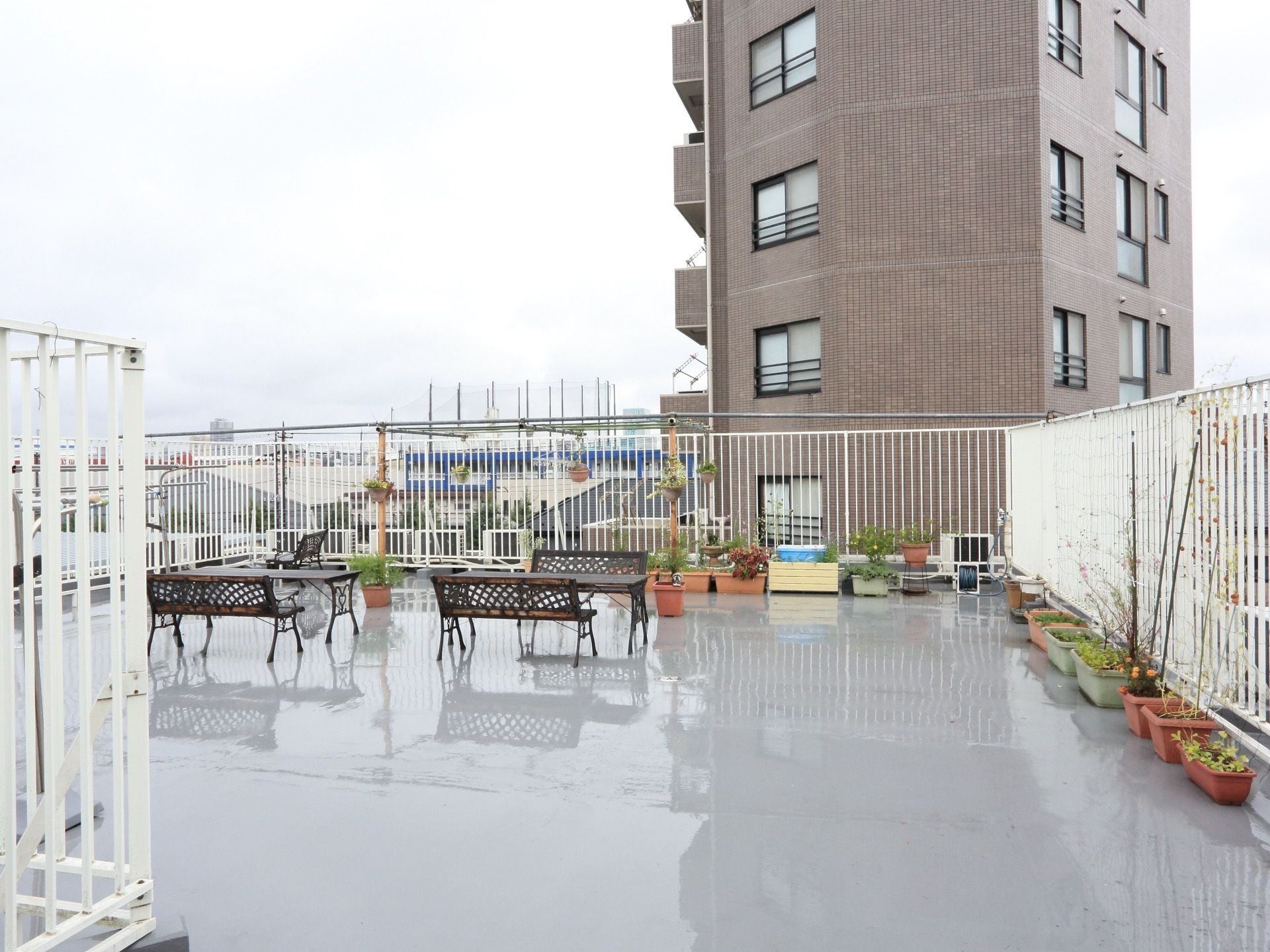 ベンチや長テーブル、物干し竿やたくさんのプランターが置かれた広い屋上