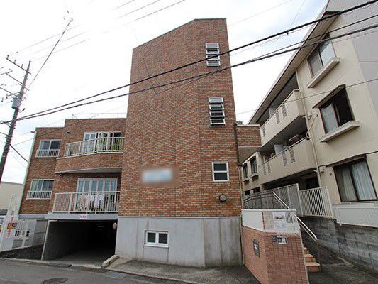 ブラウンの外壁がナチュラルな雰囲気の建物である。玄関までの通路は階段になっており、手すりがあるので安全に移動することができる。