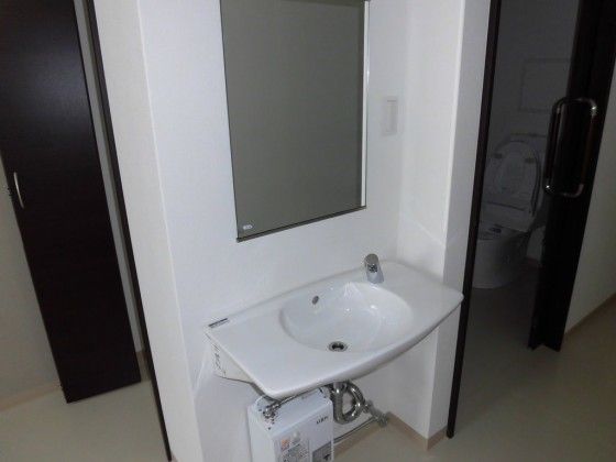 居室に備え付けられた鏡付きのシンプルな洗面台である。周辺には、トイレやクローゼットも設置されている。