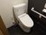 ダークブラウンと白を基調としたトイレスペースである。便器横の壁に手すり、ナースコール、トイレットペーパーホルダーなどを完備している。