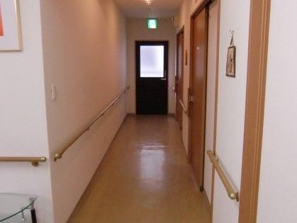 手すりが備え付けられた廊下である。天井には非常口の表示灯を設置し、常に入居者様の安全を確保できるよう配慮している。