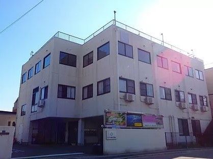 車同士がすれ違えるほどの広い門のある3階建ての白い建物